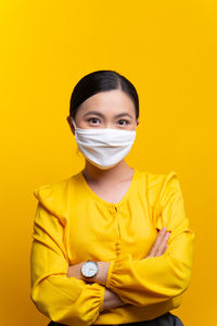 Portrait of mid adult man standing against yellow background