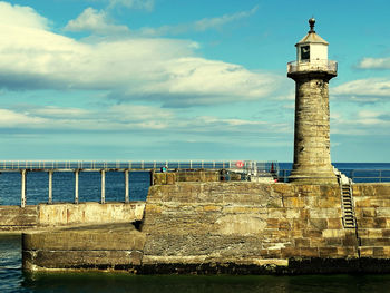 Lighthouse by sea against sky