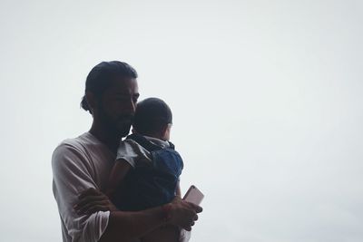 Low angle view of a man embracing his child