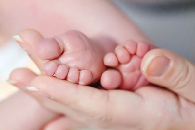Cropped hands of parent holding baby barefoot