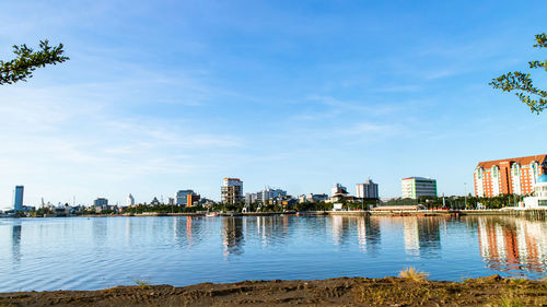 Scenic view of river by buildings against sky