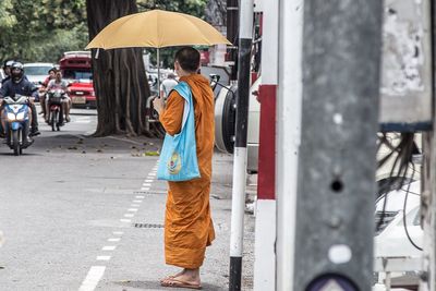 Rear view of woman walking on street during rainy season