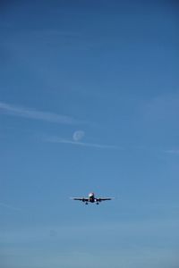 Low angle view of airplane in flight against blue sky