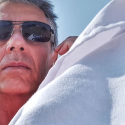 Close-up portrait of mature man wearing sunglasses against sky