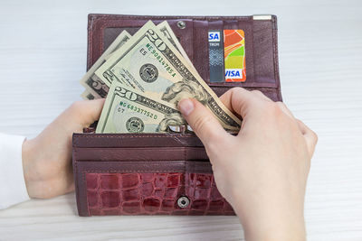 Cropped hands of woman holding paper currency in purse at table