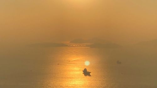 Silhouette man in sea against sky during sunset