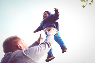 Low angle view of father and daughter playing against clear sky