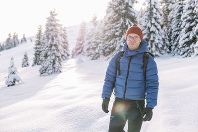 Man on a hike in the snow during winter, at sunset time.