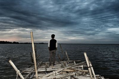 Rear view of man standing by sea against sky