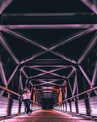 Full length of man standing on illuminated bridge at night