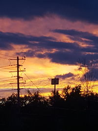 Silhouette of electricity pylon at sunset