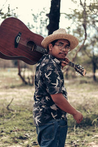 Portrait of man holding guitar on field