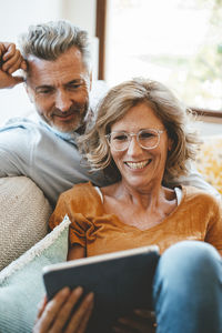 Happy woman wearing eyeglasses using tablet pc with man at home