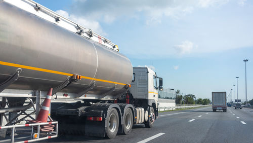 Vehicles on road against cloudy sky