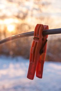 Close-up of clothespins on rope against sky during sunset