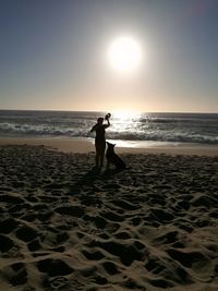 Silhouette man standing on beach against sky during sunset