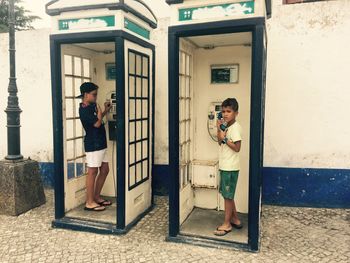 Portrait of boys standing in phone booth 