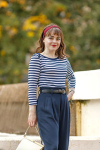 Portrait of young woman standing against railing