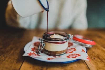 Midsection of person pouring chocolate syrup in dessert