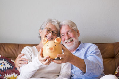 Smiling senior couple holding piggy bank