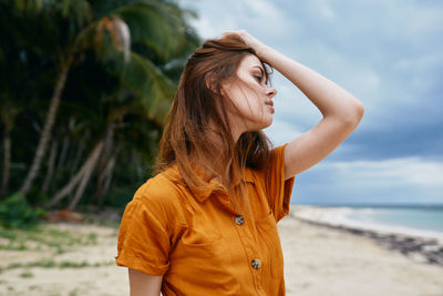 Woman looking away while standing on beach