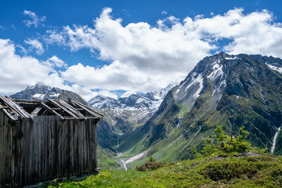 The old hut in a scenic view of mountains against sky and clouds