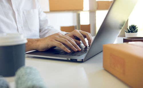 Midsection of businessman using laptop at desk in office