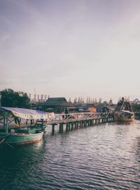 Boats moored at harbor against sky in city