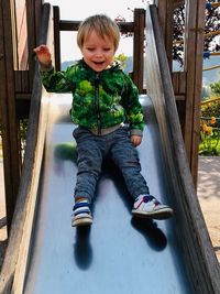 Cute boy smiling while sitting on slide