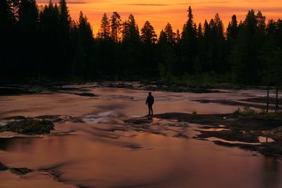 Full length of woman standing on land against sky at sunset