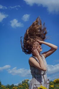 Woman tossing hair while standing at field