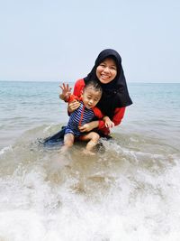 Portrait of woman with son in sea against sky