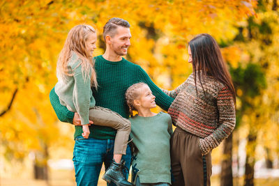 Happy friends with arms raised during autumn