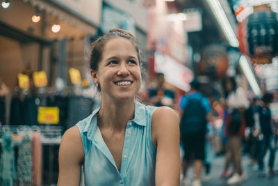 Smiling woman looking away while sitting outdoors