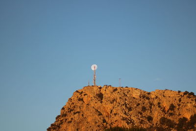 Low angle view of rocks against clear blue sky