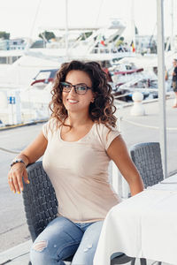 Portrait of smiling young woman sitting at cafe outdoors