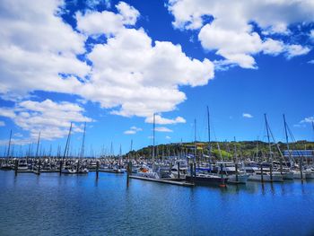 Sailboats moored at harbor against blue sky
