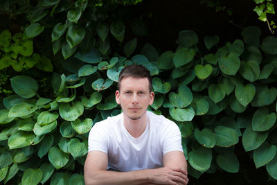 Portrait of young man against leaves