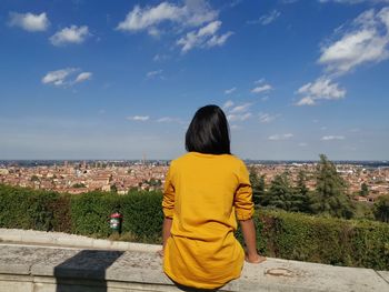 Rear view of woman looking at cityscape against sky