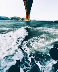 Low section of man on boat in sea against clear sky