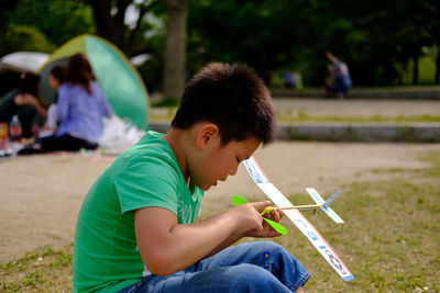 Boy playing with toy airplane at park