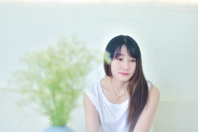 Portrait of young woman standing against wall