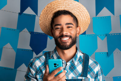 Portrait of smiling man wearing hat against wall