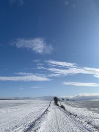 Tire tracks on road against sky during winter