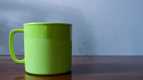 Close-up of coffee cup on table against wall