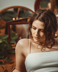 Beautiful young woman sitting infront of different mirrors.