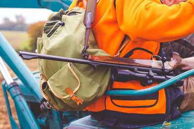 Midsection of person sitting with gun on vehicle