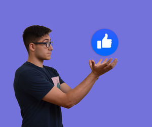 Side view of young man standing against blue background