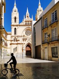 Man riding bicycle on street amidst buildings in city