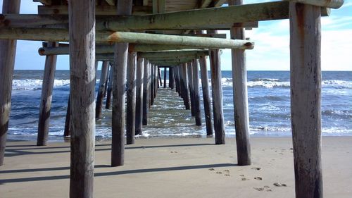 Wooden pier on beach against sky